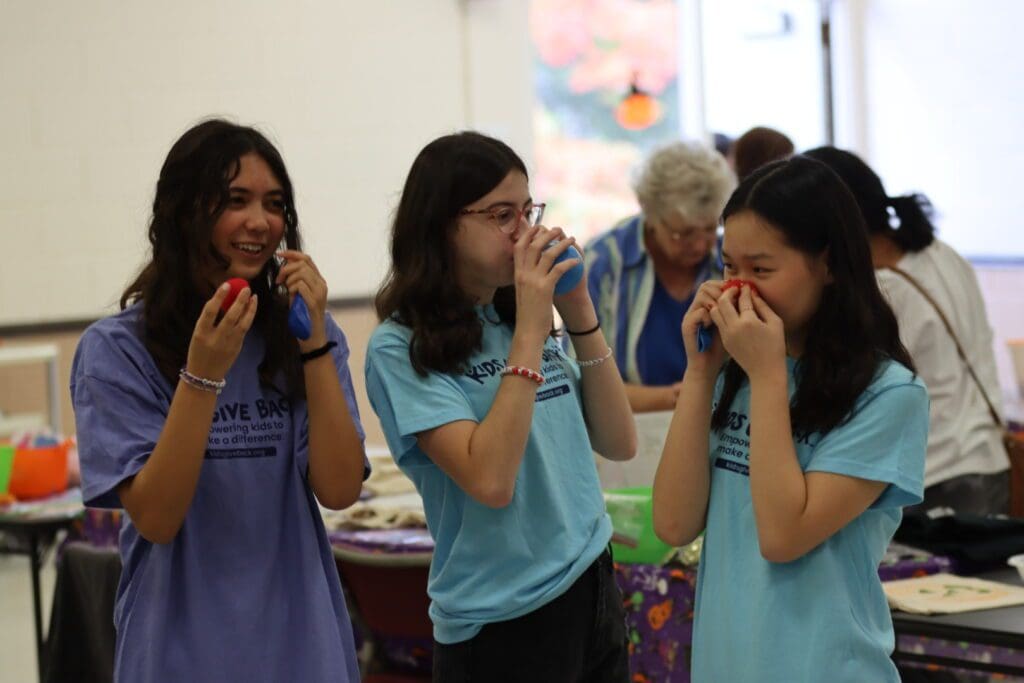 three girls are smiling with baloon in their hand